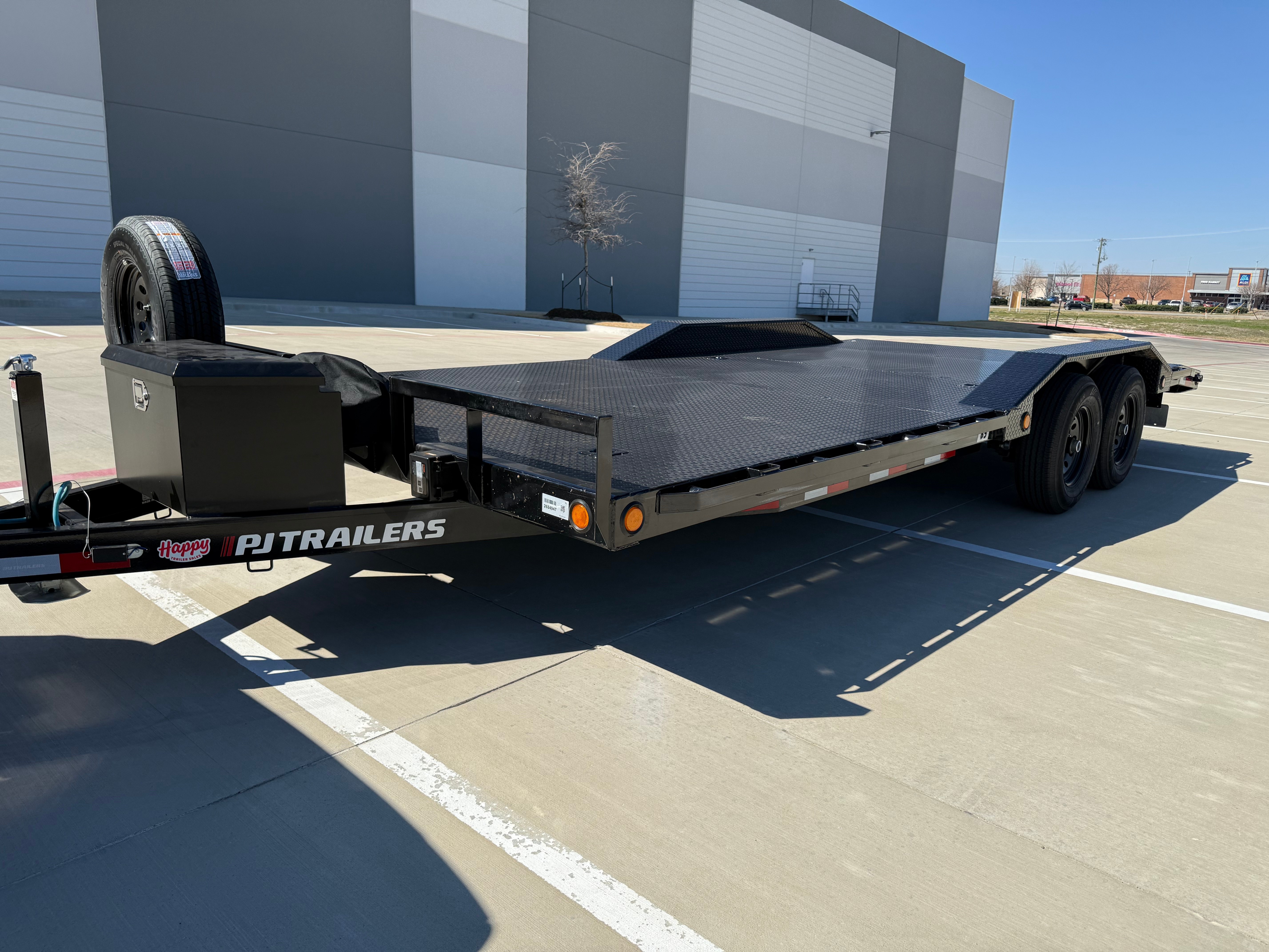 20ft flatbed car hauler with front-mounted spare tire and toolbox storage